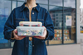 Woman holding reusable plastic containers with salad and snacks outdoors