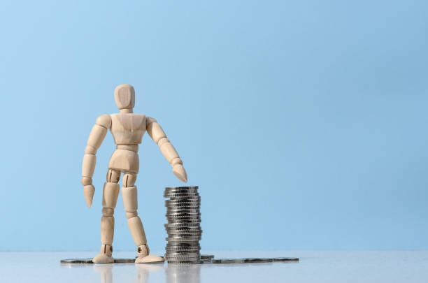 istock Wooden mannequin and a stack of coins on a blue background 1471521411