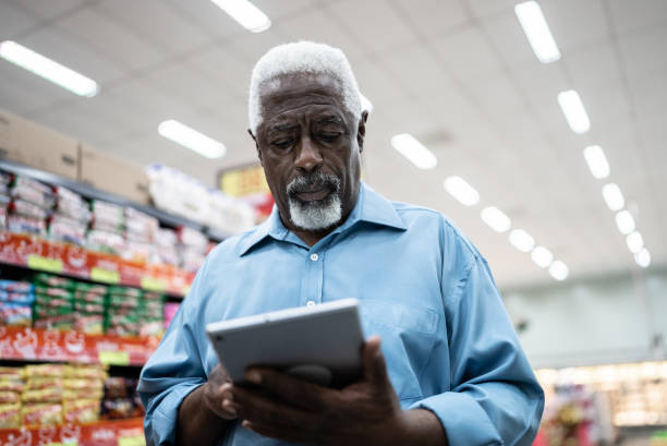 istock Senior man using on the digital tablet in the supermarket 1471522516