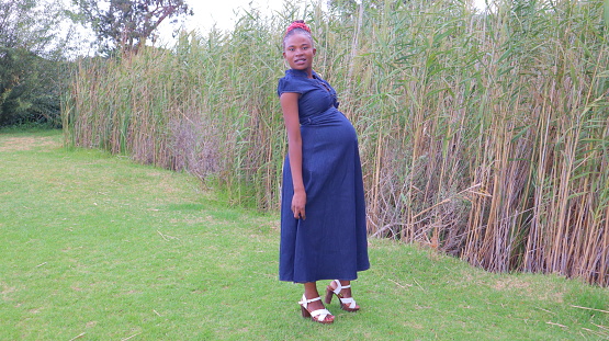 black pregnant woman standing in the park