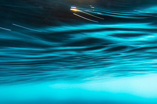 An abstract artistic scene of a wave breaking underwater in dramatic light