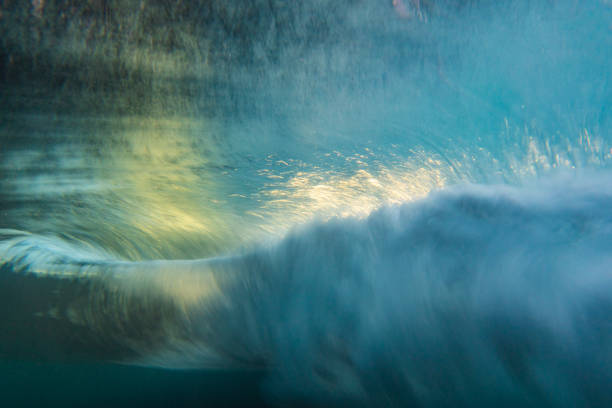 An abstract artistic scene of a wave breaking underwater in dramatic golden light. Photographed with slow shutter in camera technique.