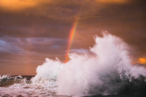 istock Ocean waves colliding under a dramatic storm pink and gold sky at sunset with rainbow 1471531215