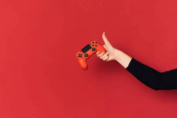 Gamepad in lady hand against red background.