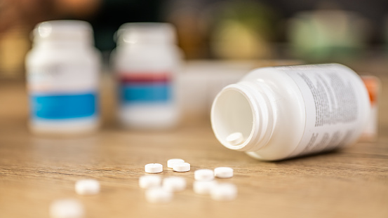 Spilled pills and empty medicine bottle on wooden table close up selective focus