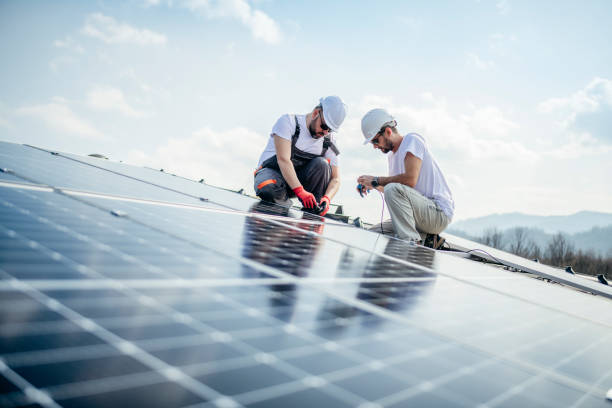 Team of two workers on a house's roof installing solar panels. stock photo