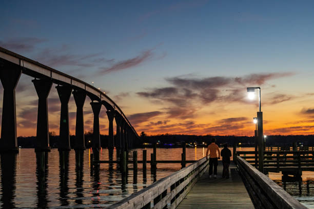 Solomons, Maryland USA Feb 28, 2023 A young couple on a pier below the the Solomons Bridge at night, or Gov. Thomas Johnson Bridge