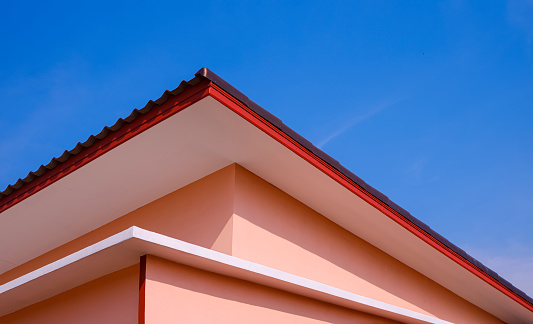 Shed roof of orange house in modern style against blue clear sky background in low angle and perspective side view.