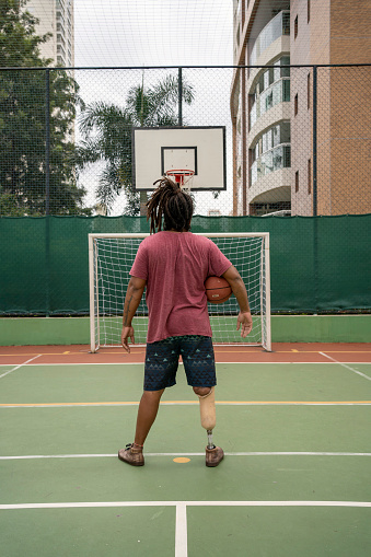 Man with leg prosthesis playing basketball