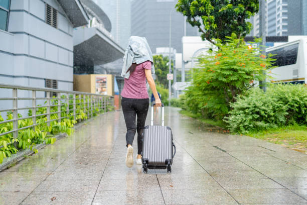 istock woman walking with suitcase in hand in rain. 1471555099