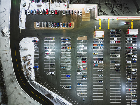 Aerial drone view of a large department store & parking lot on cold Winter night.