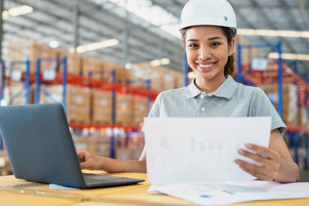istock Great working environmental increase warehouse performance and productivity. Asia warehouse worker woman using computer and input inventory data from report standing in front of the warehouse rack. Manager looking at camera with smile. 1471561292