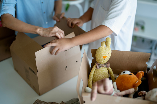 Asian woman and her son packing old clothes and stuffed toys into the donation boxes.