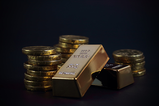 Gold coins with gold ingots on black background