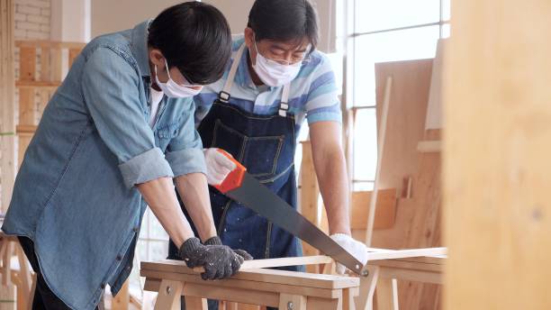 istock Asian man carpenter training showing apprentice how to use hand sawing in the workshop 1471571735