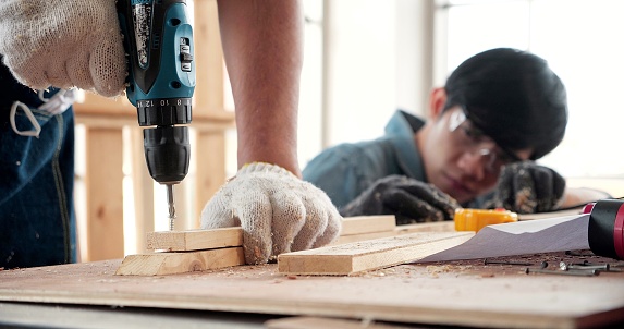Close-up of a carpenter using a wood drill to make wooden furniture