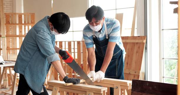istock Asian man carpenter training showing apprentice how to use hand sawing in the workshop 1471571765