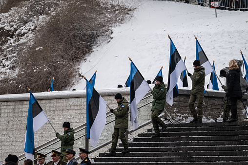 Estonian flags held by young Estonians walking down the stairs in the main square in Tallinn during the celebration of the national holiday - independence day