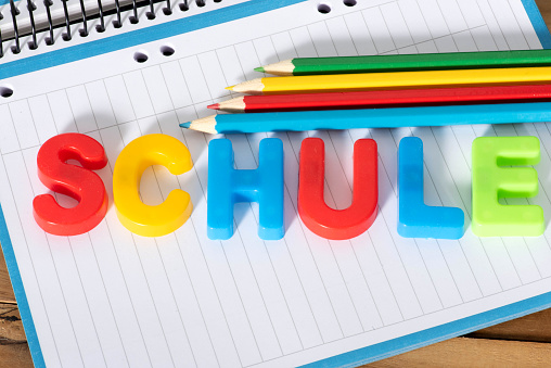 Schulsachen und das Wort Schule aus bunten Buchstaben