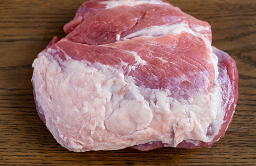 A large piece of meat fresh raw pork with a lot of fat lies on a wooden board