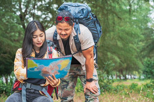 Hikers reading a map while trekking in nature. Nature. Lifestyle. People and leisure time concept. Couple hikers are looking for destinations on the map.