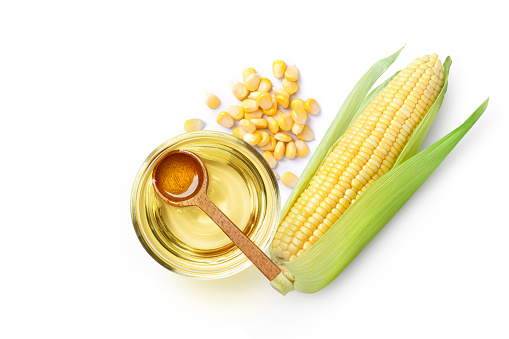 Corn oil and fresh sweet corn seeds isolated on white background. Top view. Flat lay.