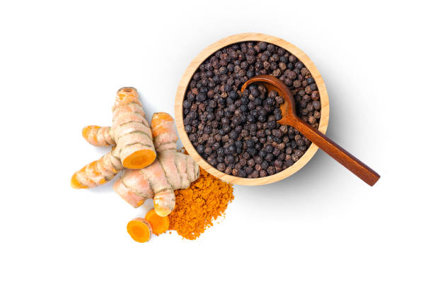 Turmeric powder (ground tumeric, curcumin, Curcuma) and black pepper corn Turmeric powder (ground tumeric, curcumin, Curcuma) and black pepper corn in wooden bowl isolated on white background. Top view, flat lay. anti inflammatory stock pictures, royalty-free photos & images