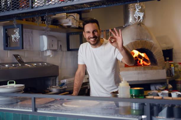 istock Handsome chef presenting pizza in a commercial kitchen. 1471579324