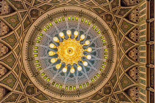 The photo gives the view of the centerpiece of the mosque's main prayer hall, which is an enormous chandelier that hangs from the ceiling. It is made of brass and decorated with thousands of Swarovski crystals, which sparkle and reflect the light in mesmerizing patterns. The chandelier is a marvel of craftsmanship and design, measuring 14 meters in diameter and weighing 8.5 tons. It is suspended from the ceiling by a system of chains and ropes, and it illuminates the prayer hall with its warm and welcoming glow.
Overall, the ceiling and chandelier of the Sultan Qaboos Grand Mosque in Muscat, Oman, are truly breathtaking works of art. They combine the traditional Islamic motifs and calligraphy with modern materials and technology to create a stunning masterpiece that reflects the beauty and majesty of Islam.