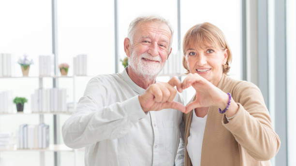 istock Elderly couple. Joyful nice elderly couple smiling while being in a great mood. Beautiful senior couple embracing each other, sitting on the couch at home 1471583485