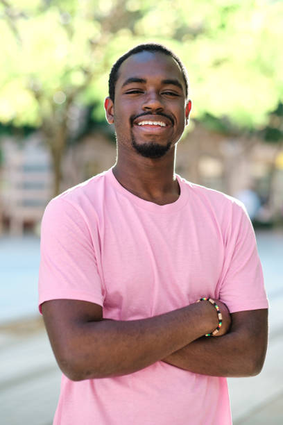 istock Man looking at camera and smiling while posing with arms crossed outdoors. 1471583530