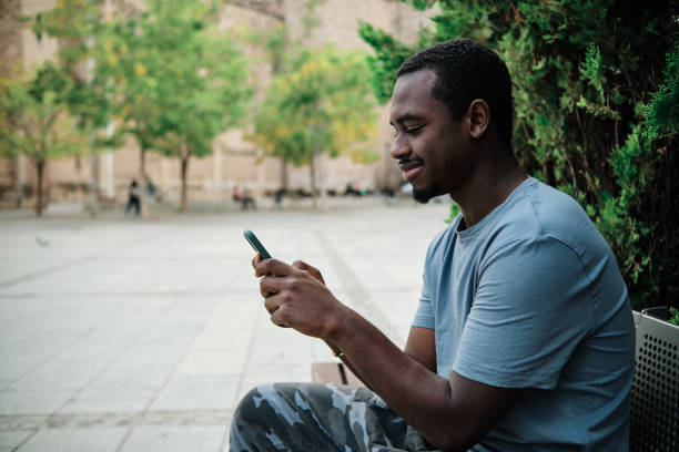 istock Man using a mobile phone sitting on a bench outdoors. 1471583558