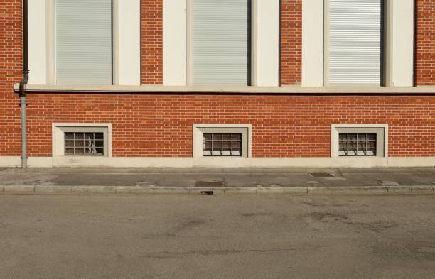istock Basement windows on brick wall facade with tarmac sidewalk and urban road in front. 1471584487