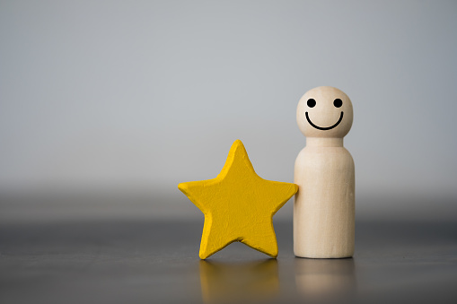 Wooden figures peg doll standing together with a yellow star. Talent, Human resources. Stand out from the crowd. Different and individual unique person. Spotlight shining to the best person