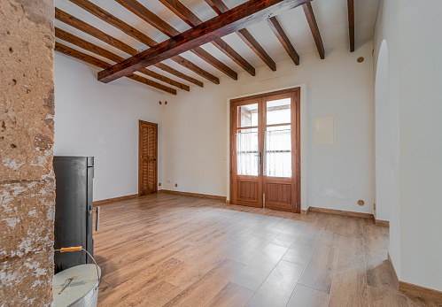 Empty living room of a town house with wooden beams, wooden floors and a stone wall