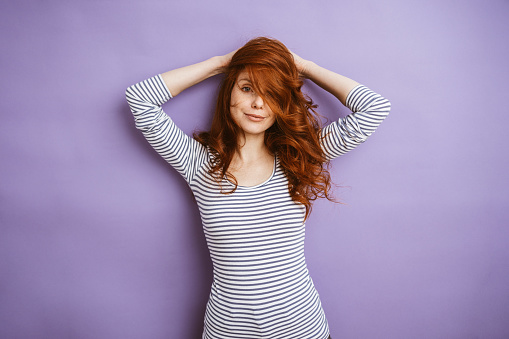 A young redhead woman with long red hair smiles happily in this studio shot portrait session.