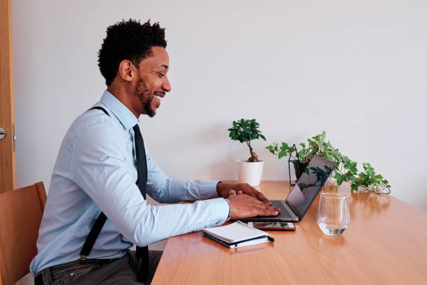 istock Professional businessman smiling while working with laptop sitting on a desk. 1471587693