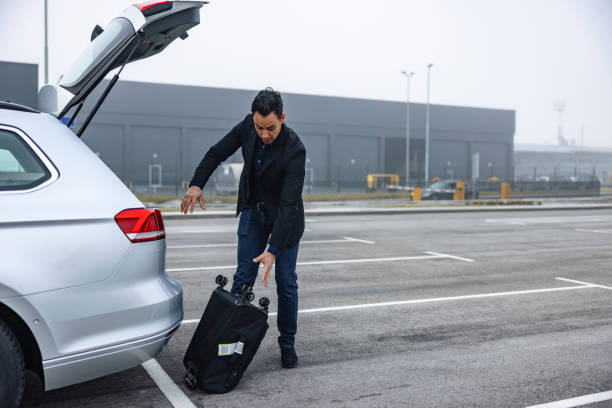 Man Accidentally Dropping A Hand Luggage Case Out Of A Car