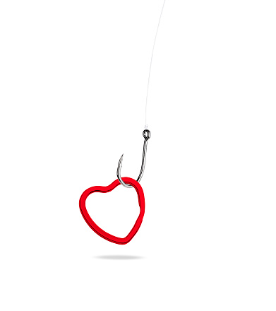 Close-up of red heart shaped ring with fishing hook against white background.