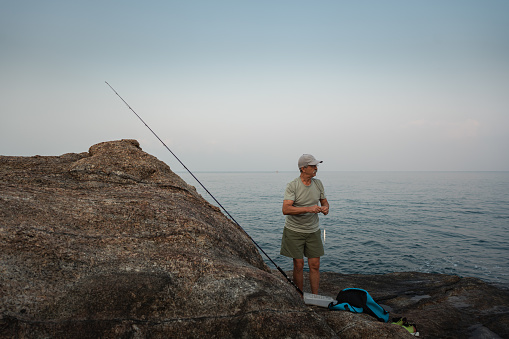 Fisherman with rod and catch on yellow background, space for text