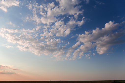 Section of blue sky with altocumulus clouds above the agricultural fields before summer sunset