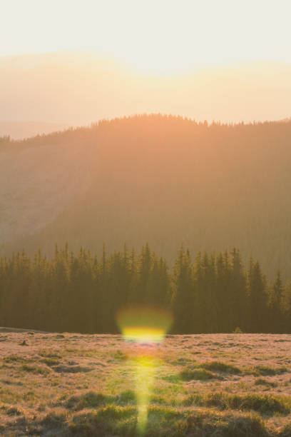 Sun glowing behind mountains silhouette landscape photo. Nature scenery photography with sunny mist on background. Ambient rim light. High quality picture for wallpaper, travel blog, magazine, article