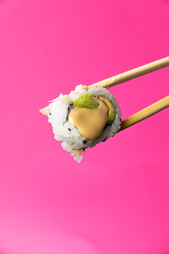 Uramaki Sushi with chopsticks on a pink background