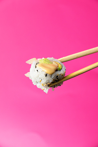 Uramaki Sushi with chopsticks on a pink background