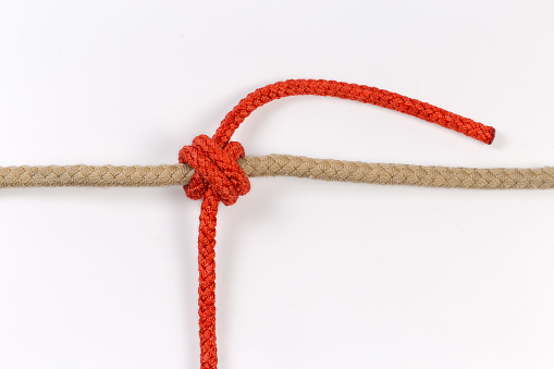 Tightened rope Double constrictor knot tied with an accessory cord around the thick rope on a white background