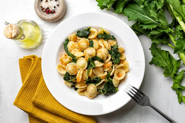 Photo of Top view of pasta Orecchiette con le cime di rapa e le acciughe popular in Southern Italy dish, typical of Apulia. Made with anchovy, bread crumbs and rapini, also called broccoli rabe or turnip greens.