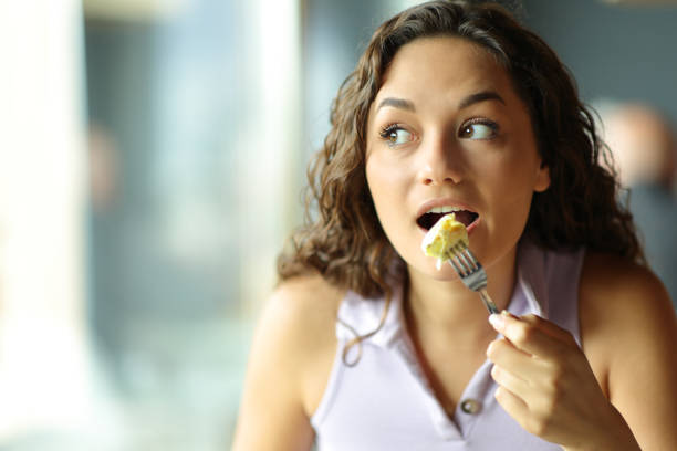 横を見てオムレツを食べる女性 - tasting women eating expressing positivity ストックフォトと画像