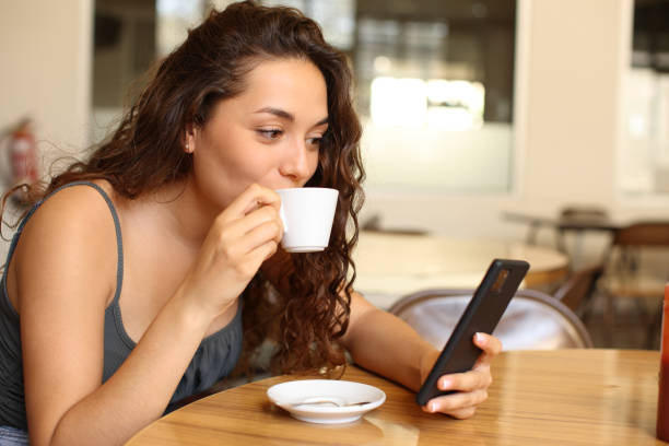 istock Woman in a restaurant drinking and checking phone 1471598526