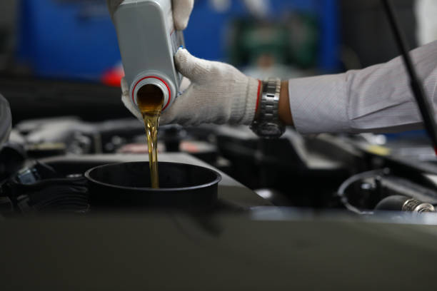 istock Car mechanic pours engine oil into car engine closeup 1471599688