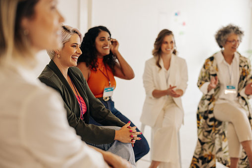 Multicultural businesswomen smiling cheerfully during a conference meeting in a modern workplace. Group of successful businesswomen working together in an all-female startup.